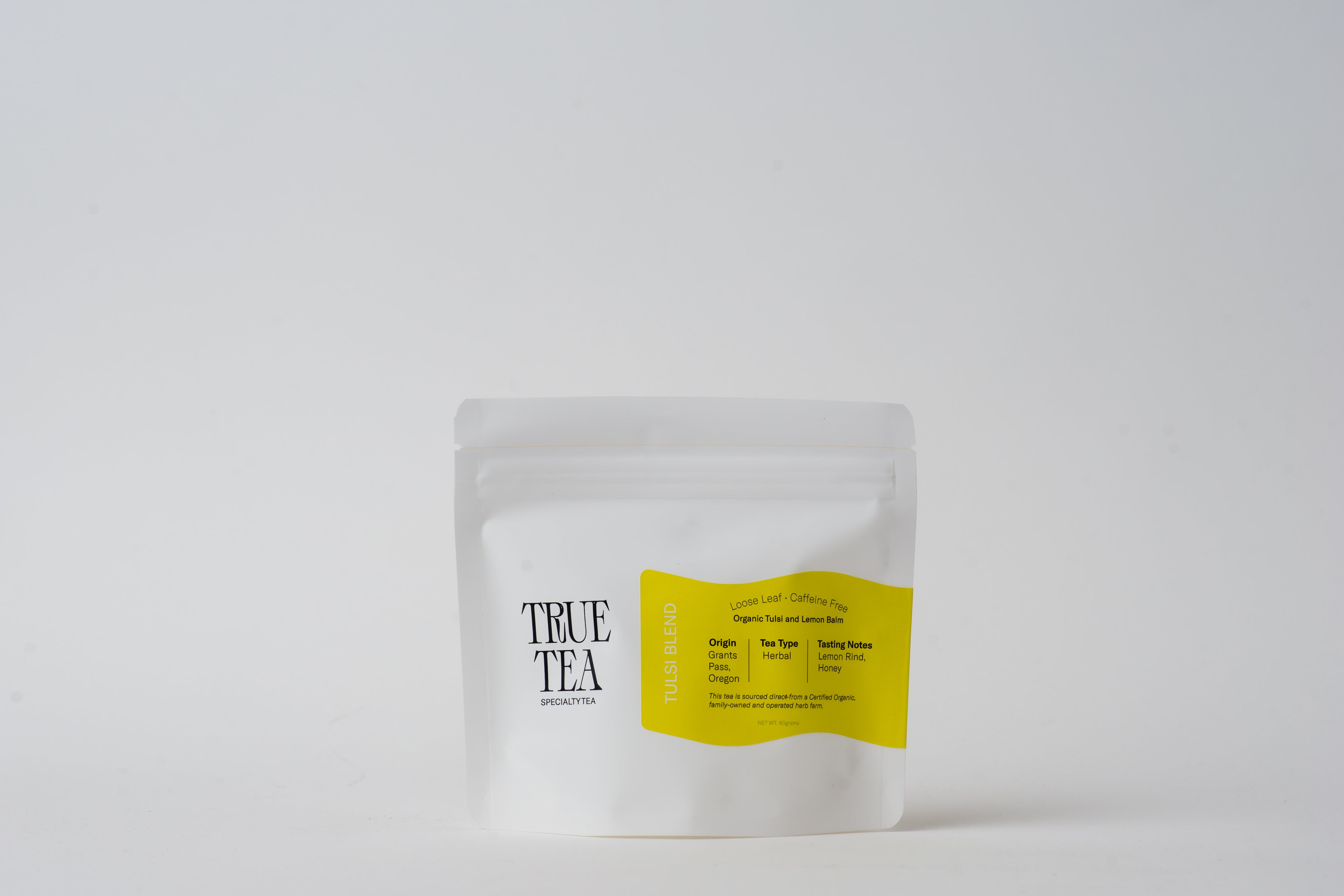 White package with a yellow label. Package contains loose leaf Organic Tulsi Blend tea from True Tea, a tea company based in Portland, Oregon